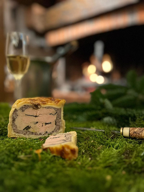 Au premier plan : découpe d'un pâté de fois gras Maréchal des Contades, au second plan : une flute de champagne